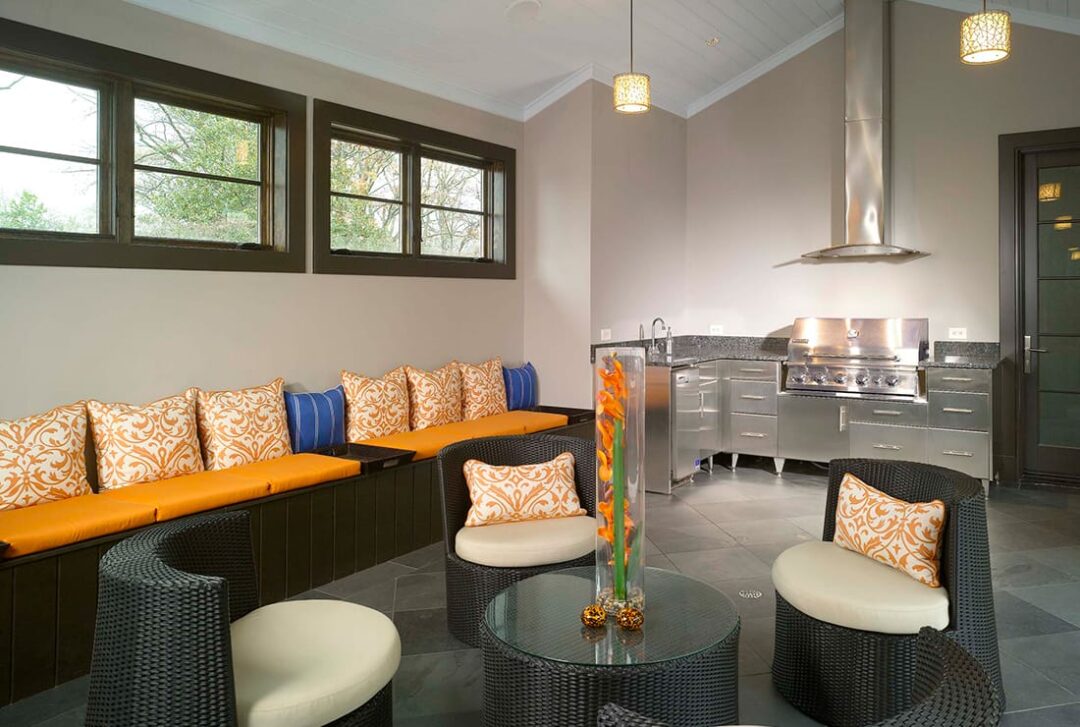 Outdoor kitchen with stainless steel grill, wicker chairs, and orange cushions in Atlanta, GA